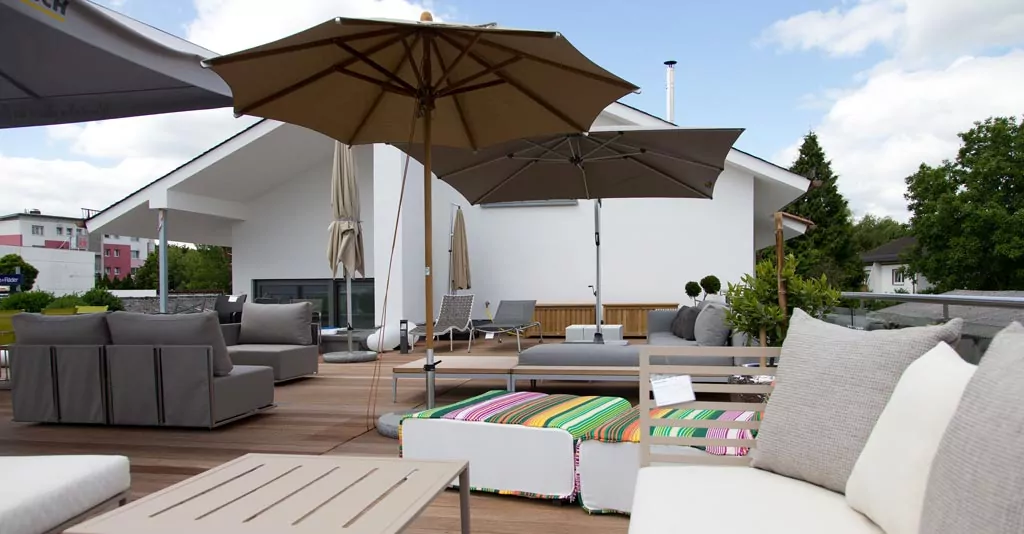 Abendliche Terrasse mit beleuchtetem rotem Sonnenschirm Braune Sonnenschirme mit Sitzecke