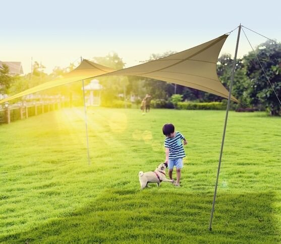 Automatische Terrassenbeschattung mit Fernbedienung Beiges Sonnensegel mit kleinem Jungen darunter beim Spielen mit dem Hund
