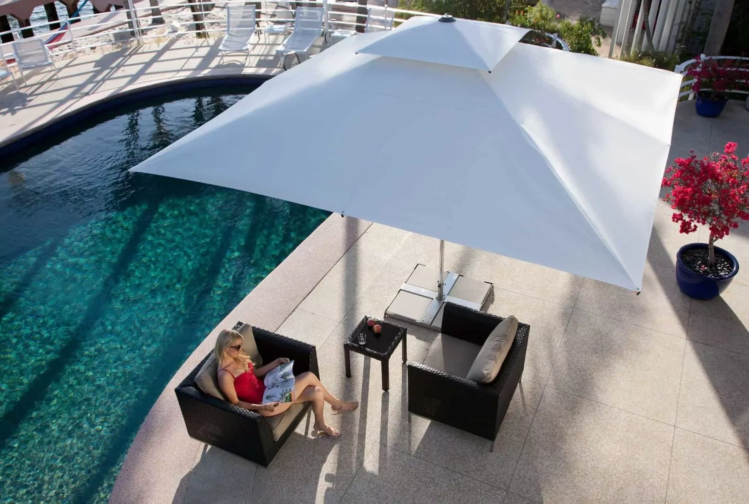 Abendliche Terrasse mit beleuchtetem rotem Sonnenschirm Weißer Sonnenschirm über der Sitzecke neben dem Pool