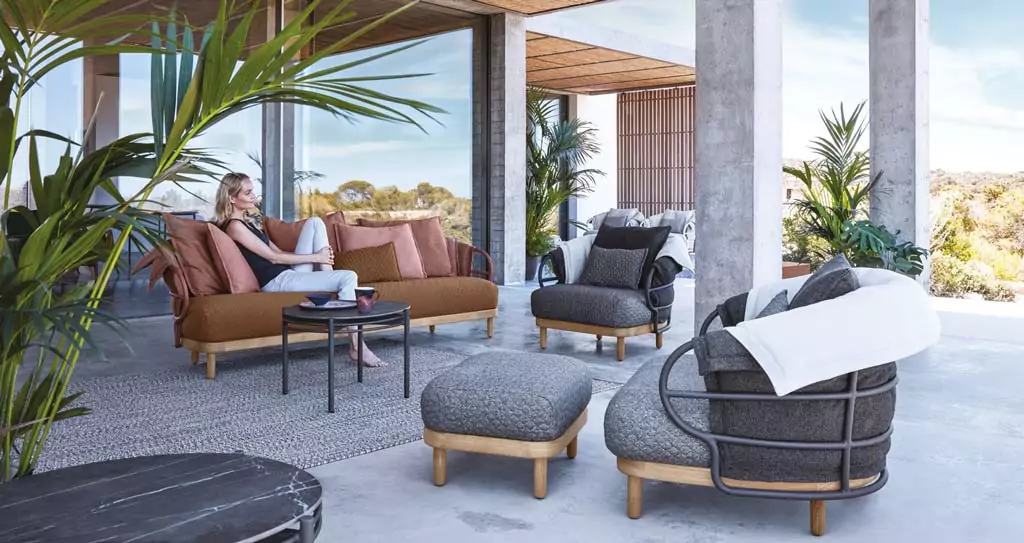Outdoor Sitzbereich mit braunem Sofa und grauen Sesseln