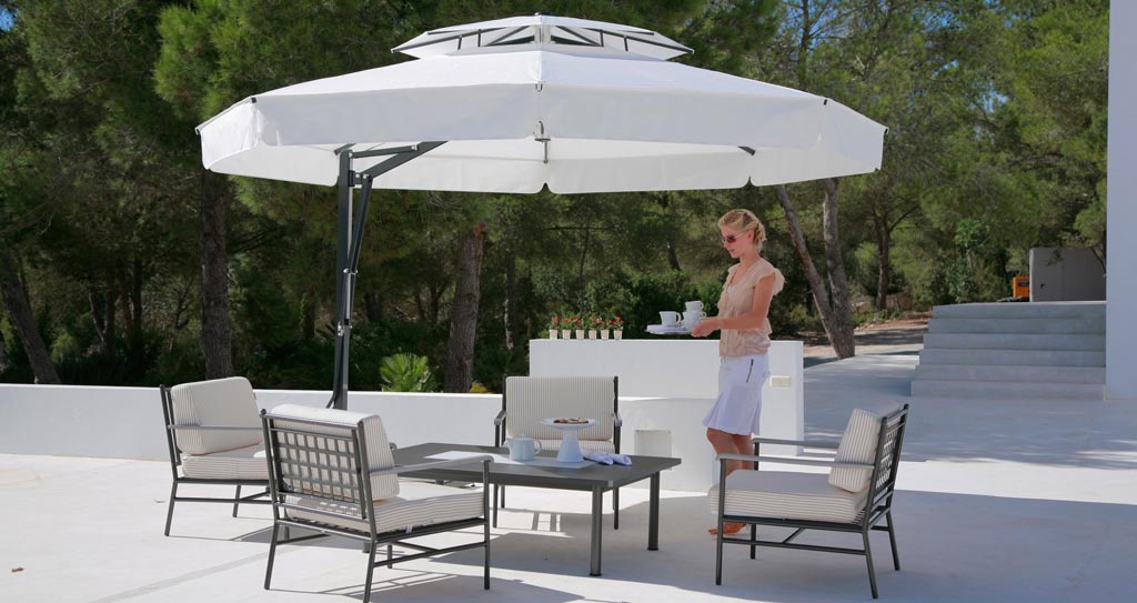 Frau steht unter May-Sonnenschirm mit Tisch und Stühlen