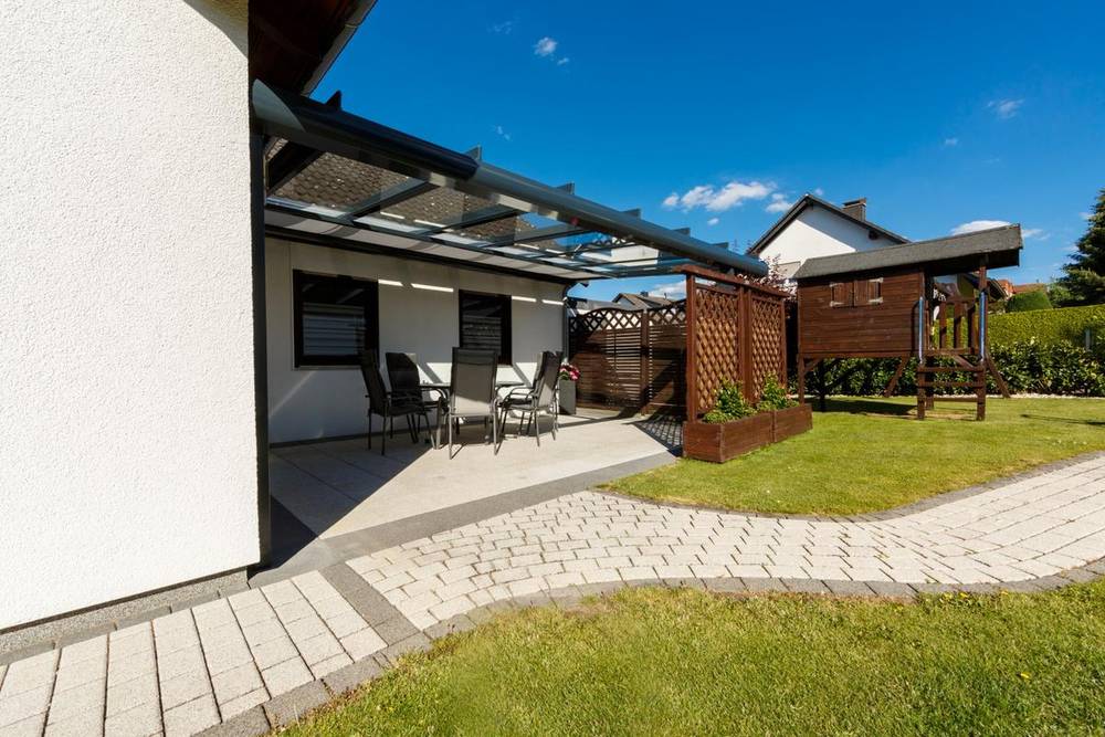 Helles Haus neben Garten und Terrasse mit Überdachung