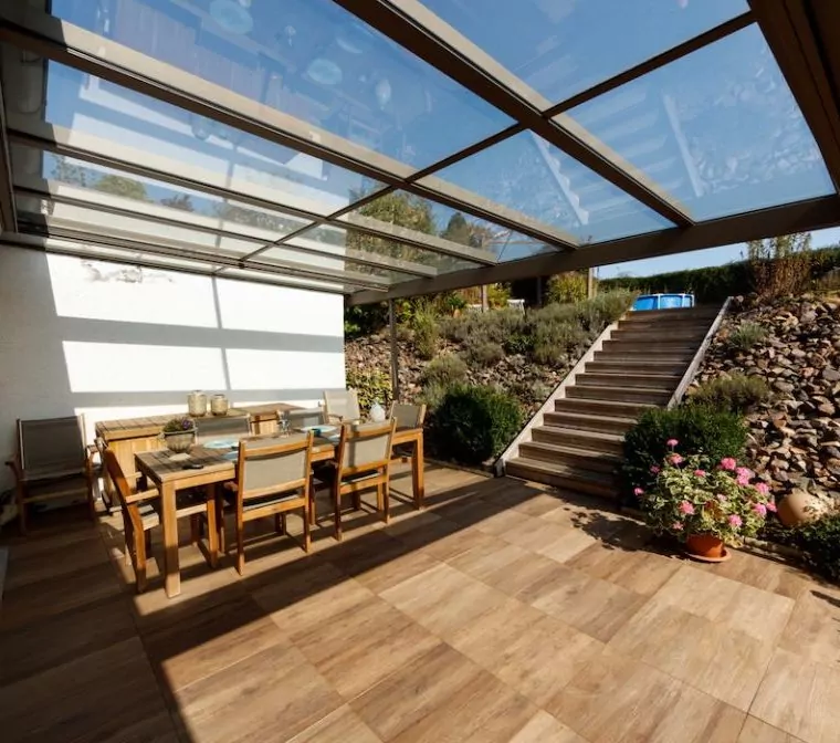 Verglastes Terrassendach über Terrasse mit braunem Holzboden